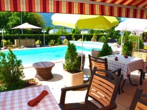 um pátio com mesas e guarda-sóis ao lado de uma piscina em The Originals City, Hôtel du Faucigny, Cluses Ouest em Scionzier