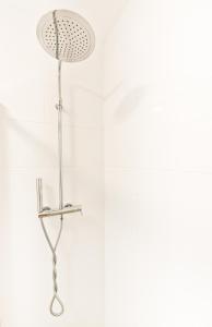 a shower in a bathroom with a white wall at Julia Apartment in Toruń