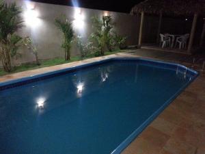 a blue swimming pool at night with lights on it at Pousada Brisa Do Pontal in Fortim