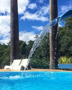 a water fountain in a swimming pool with a chair at Pousada Cantinho do Mundo in Brumadinho