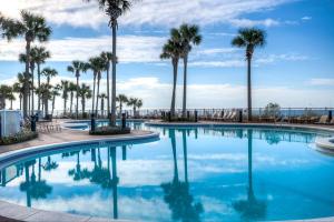 une piscine avec des palmiers et l'océan en arrière-plan dans l'établissement Grand Panama Resort 2-202 By Aneliya, à Panama City Beach