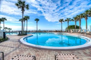 a swimming pool with palm trees and chairs at Grand Panama Resort 2-202 By Aneliya in Panama City Beach +62 photos