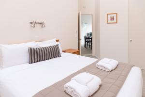 - une chambre avec un grand lit blanc et des serviettes dans l'établissement Courtenay Village, à Wellington
