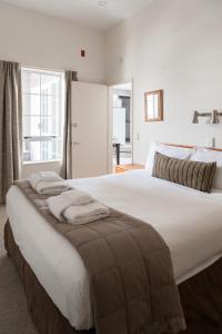 a bedroom with a large white bed with towels on it at Courtenay Village in Wellington