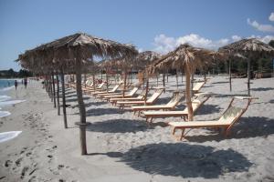 a row of chairs and straw umbrellas on a beach at Hotel Baia Cea in Bari Sardo
