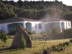 a house with a rock in front of it at Hotel Baia Cea in Bari Sardo