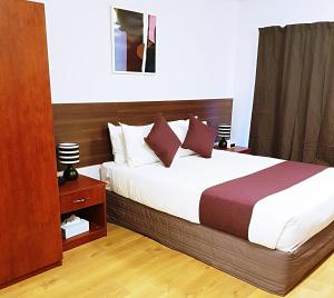 a bedroom with a large bed with a wooden headboard at Airport Garden Inn Hotel & Conference Centre in Auckland