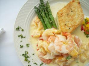a plate of food with shrimp and asparagus and a cracker at Bar Harbor Inn and Spa in Bar Harbor