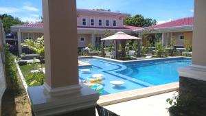 einen Pool mit Sonnenschirm und Stühlen und ein Haus in der Unterkunft Venezia Suites Resort Panglao in Panglao