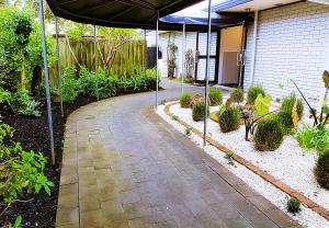 an umbrella over a walkway in a garden at Airport Garden Inn Hotel & Conference Centre in Auckland