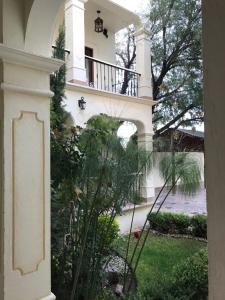 a white house with a balcony and a garden at Hotel Mariazel in Bernal