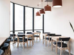 - une salle à manger avec des tables, des chaises et des fenêtres dans l'établissement Abode Kingston, à Canberra