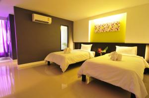 Habitación de hotel con 2 camas con sábanas blancas en At 24 Boutique Hotel, en Nakhon Si Thammarat
