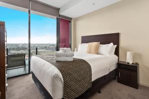 a bedroom with a large bed with a large window at Docklands Private Collection - NEWQUAY in Melbourne