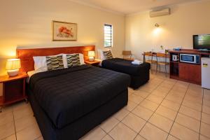 a bedroom with two beds and a kitchen with a tv at Cairns Queens Court in Cairns