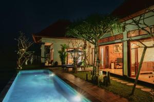 a swimming pool in front of a house at night at Umah Sunset in Ubud