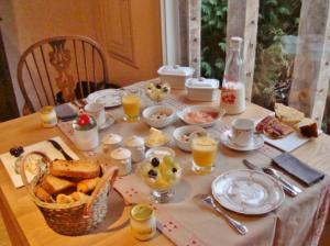 un tavolo con colazione a base di pane tostato e succo d'arancia di Guest House Le Clos Pasquier a Blois