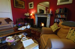 a living room with a fireplace and a couch and a table at Castlemead Country House By The Sea in Manorbier