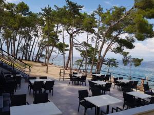 une terrasse avec des tables et des chaises et l'océan dans l'établissement Apartments Mare & Mons Deluxe, à Malinska