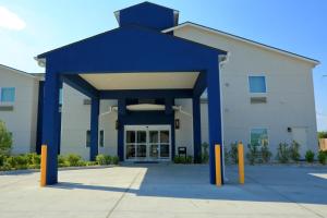 a large building with blue pillars in front of it at Americas Best Value Inn & Suites-Prairieville in Prairieville 