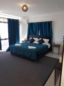 1 dormitorio con cama azul y cortinas azules en The Q Motel Rockhampton en Rockhampton