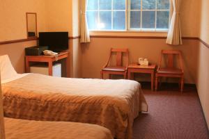 a hotel room with two beds and two chairs and a window at Atami Hotel Paipuno Kemuri in Atami