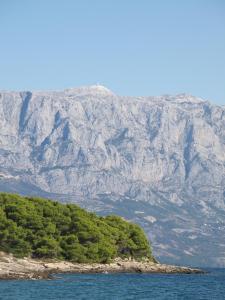 an island in the water with a mountain in the background at Apartments Adria Blue in Jelsa