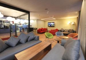 sala de estar con sofá, mesas y sillas en Weissbad Lodge, en Weissbad