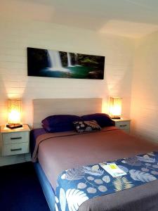 a bedroom with a bed and two night stands with lamps at Dampier Mermaid Hotel Karratha in Dampier