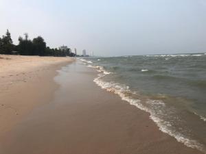 an empty beach with the ocean and buildings in the distance at rain condo 2 bedroom by leelawadee in Cha Am