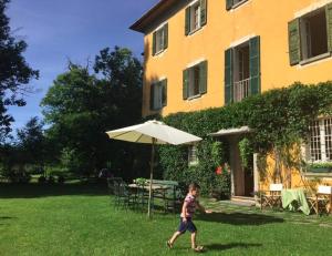 Un bambino che cammina nell'erba con un ombrello di Hotel Villa Simplicitas a San Fedele Intelvi