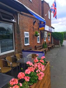 a cafe with tables and flowers in front of a building at Redbeck Motel in Wakefield