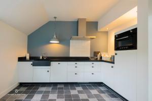 uma cozinha com armários brancos e um balcão preto em Woonboerderij Dijkerhoek em Holten