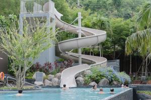 eine Rutsche in einem Pool mit Menschen im Wasser in der Unterkunft Unixx Pattaya by Alvin in Pattaya South