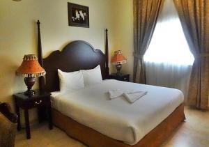 a bedroom with a large bed with two lamps and a window at Sara Hotel Apartments in Ajman 