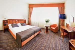 una camera d'albergo con un grande letto e una scrivania di Luxury Family Hotel Bílá Labuť a Praga