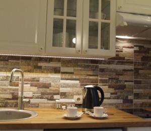 um balcão de cozinha com duas chávenas e um lavatório em Centro apartamentai em Druskininkai