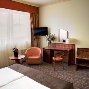 una camera d'albergo con letto, scrivania e sedia di Luxury Family Hotel Bílá Labuť a Praga
