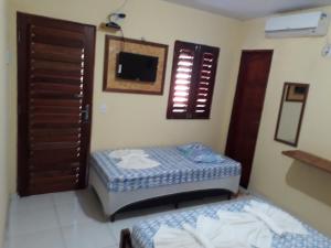 a small room with two beds and a tv at Pousada Brisa de Flecheiras in Flecheiras