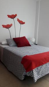 Una cama con dos flores rojas encima. en Centro Histórico de Málaga, en Málaga