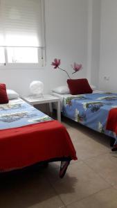 a bedroom with two beds and a table and a window at Centro Histórico de Málaga in Málaga