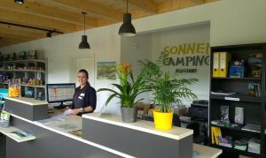 a woman sitting at a desk in an office with plants at Bungalows am Sonnencamping Albstadt - oberhalb Badkap in Albstadt