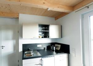 eine Küche mit weißen Schränken und einer schwarzen Arbeitsplatte in der Unterkunft Bungalows am Sonnencamping Albstadt - oberhalb Badkap in Albstadt