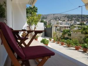 a wooden table and chair on a balcony with plants at Vila Alikaj in Sarandë