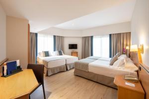 um quarto de hotel com duas camas e uma escrivaninha em Hotel Praga em Madrid mais 37 fotografias