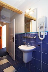 Baño de azulejos azules con lavabo y espejo en Hotel Pod Sluncem, en Třebíz