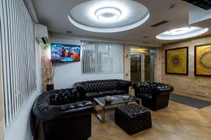 a living room with black leather couches and a table at Olympic Apartments& Spa in Belgrade