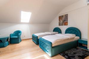 a bedroom with two beds and blue chairs at Olympic Apartments& Spa in Belgrade