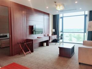 a hotel room with a desk and a large window at Becamex Hotel New City in Thu Dau Mot