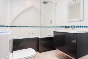 a bathroom with a tub and a toilet and a sink at Sea View Penthouse Maisonette in Brighton & Hove